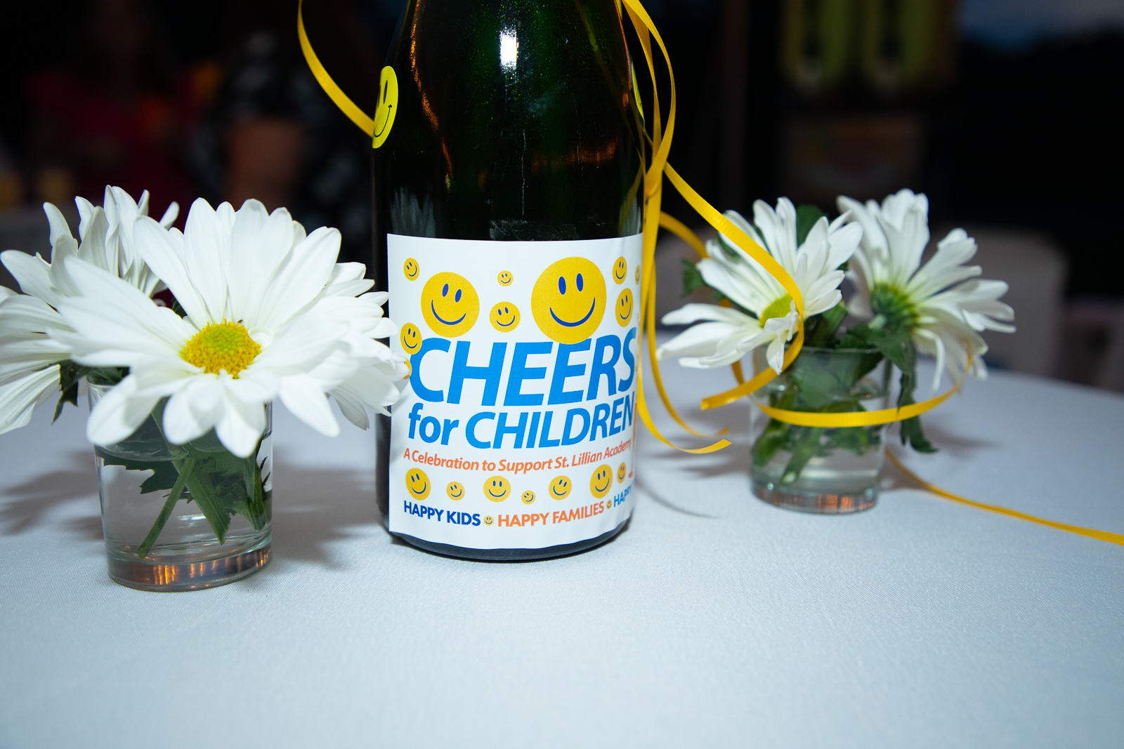 Cheers for Children Champagne bottle on table with flowers